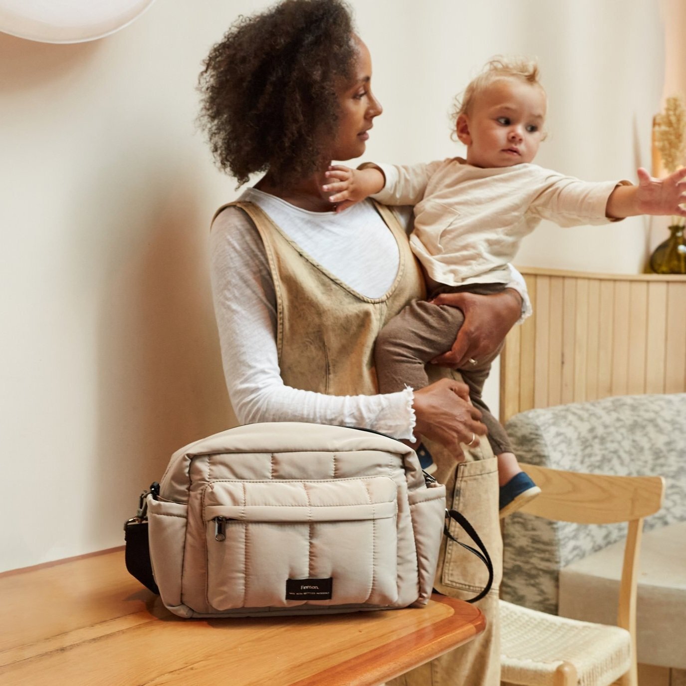 FINNSON FREYA OVERSIZED STROLLER ORGANISER TAUPE ON TABLE MODEL HOLDING BABY