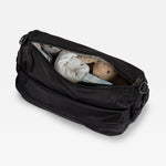 The Finnson Clara diaper bag shown open, containing baby clothes and a teddy bear, on a light gray background.