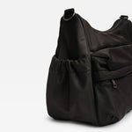 Clara changing bag in black nylon bag with a drawstring front pocket and a zippered side pocket, photographed on a clean white background.