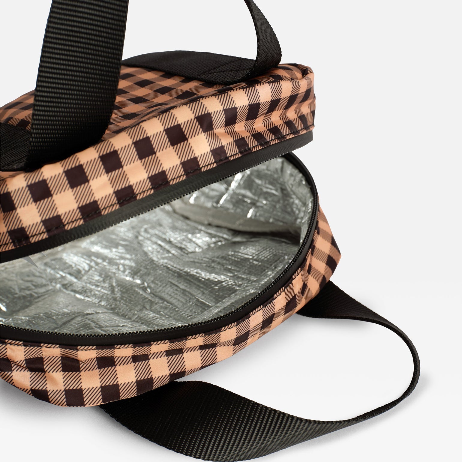 A close-up of Ebba gingham check patterned lunch/snack cool bag and its fully thermo-insulated lining exterior, black webbing handles.