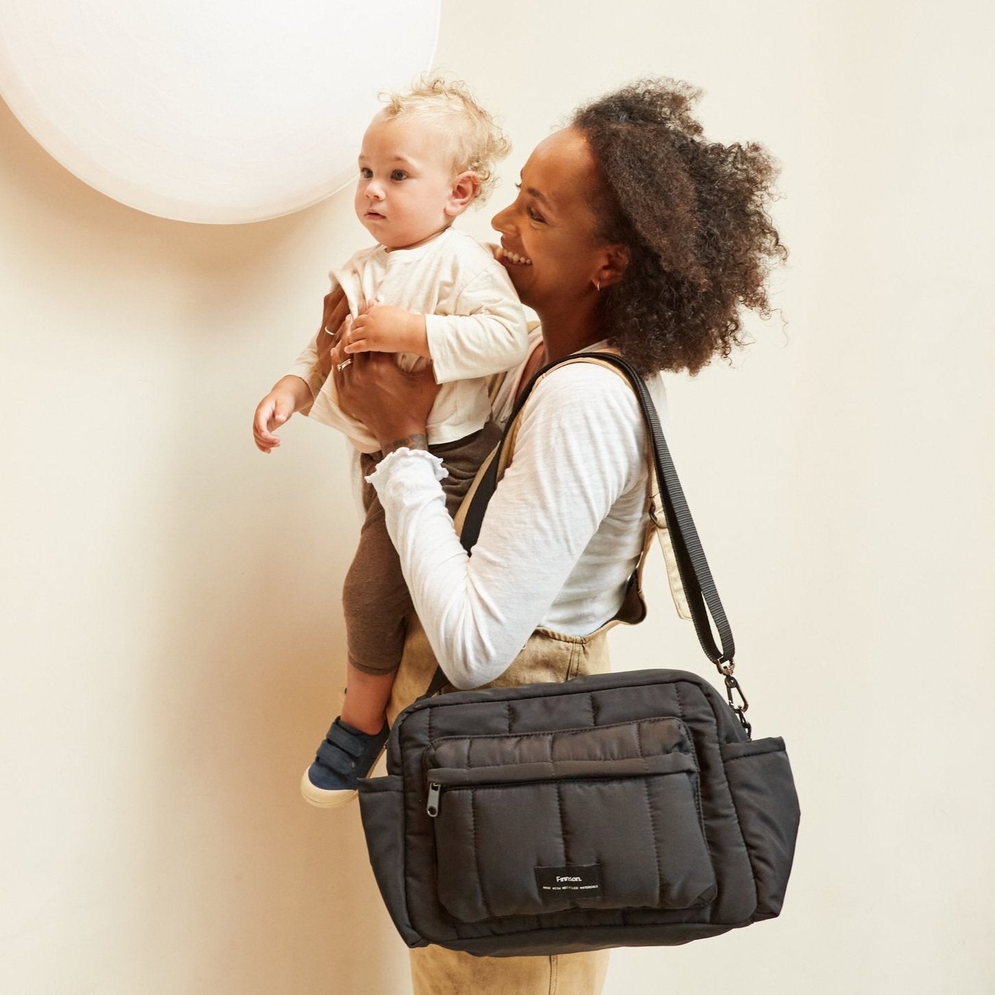 FINNSON FREYA OVERSIZED STROLLER ORGANISER BLACK MODEL WEARING ON SHOULDER HOLDING BABY 