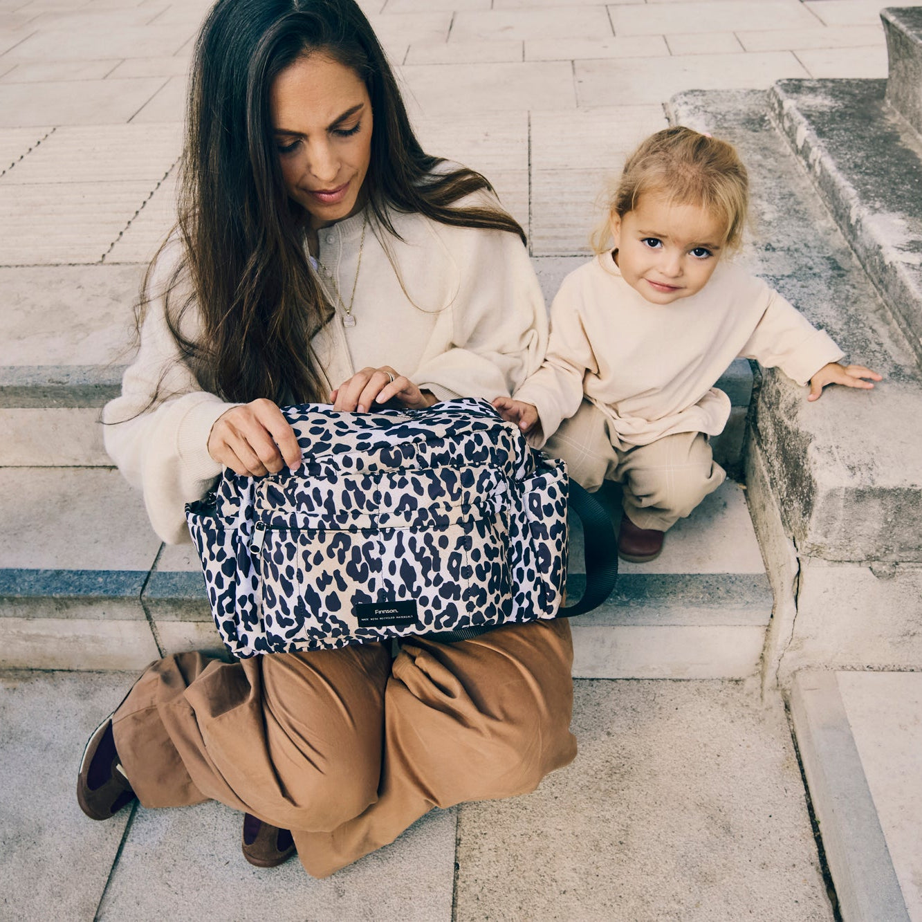 Woman and child sitting on steps with a Freya leopard print bag