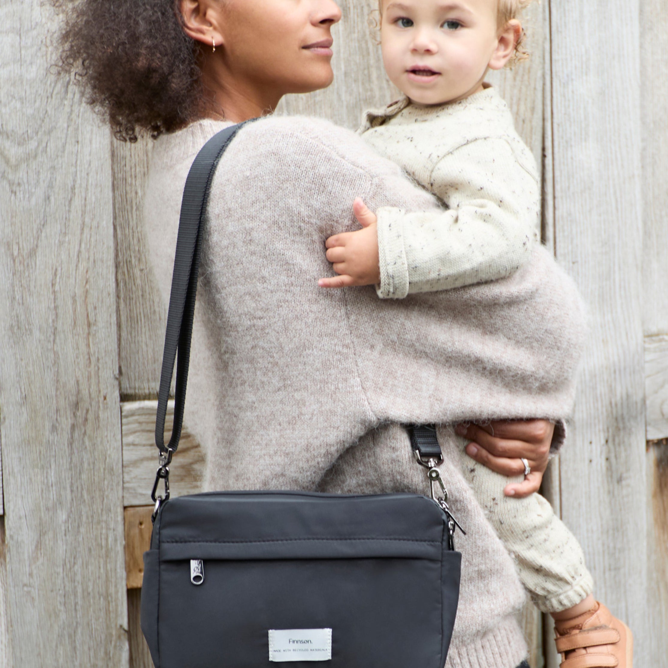 FINNSON FRIDA STROLLER ORGANISER BLACK MODEL WEARING ON SHOULDER HOLDING BABY 