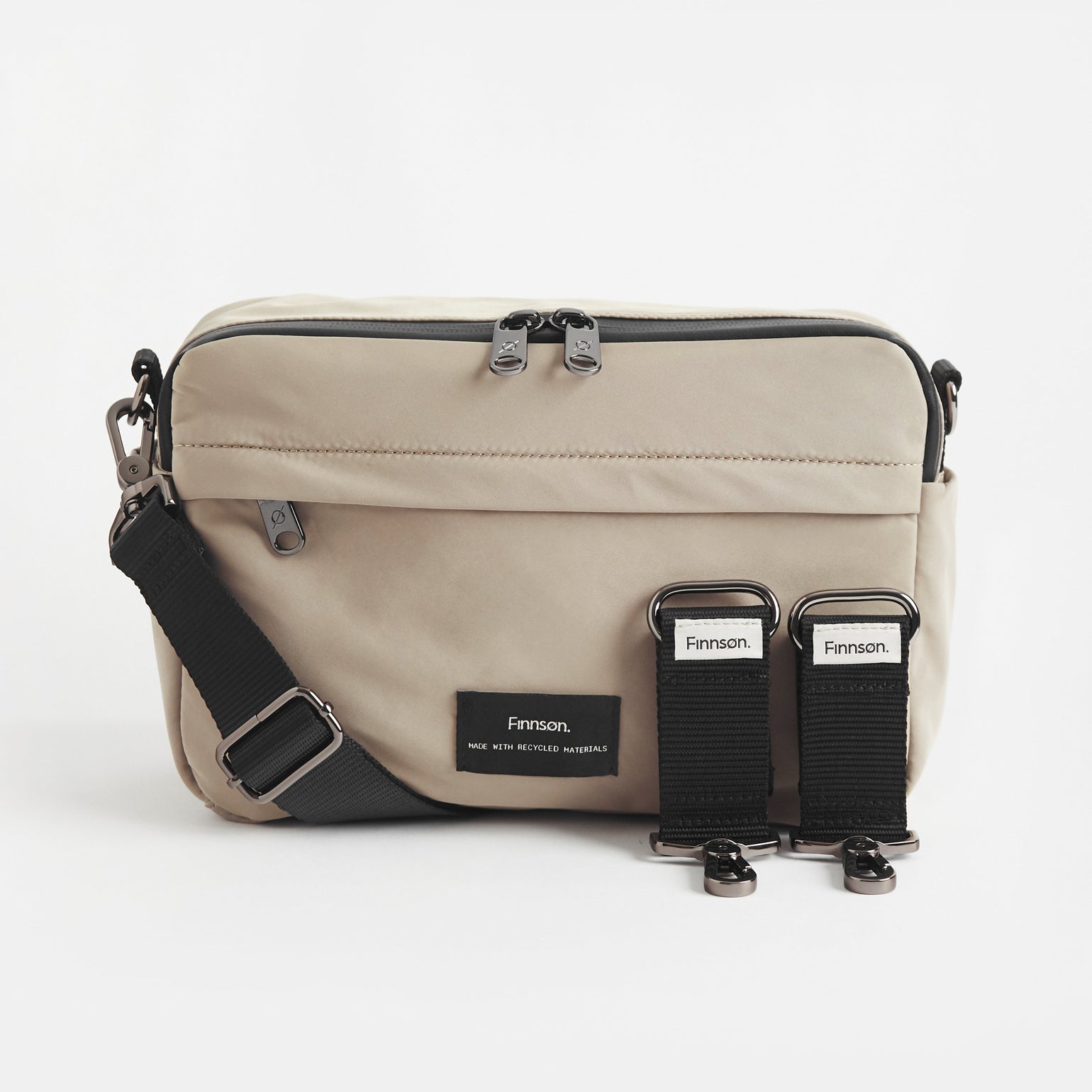A taupe Frida stroller organiser with a comfortable crossbody strap and stroller clips, featuring multiple pockets with a grey interior, designed for easy access.