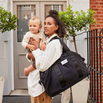 FINNSON IDA HOLDALL BLACK MODEL WEARING ON SHOULDER HOLDING BABY 