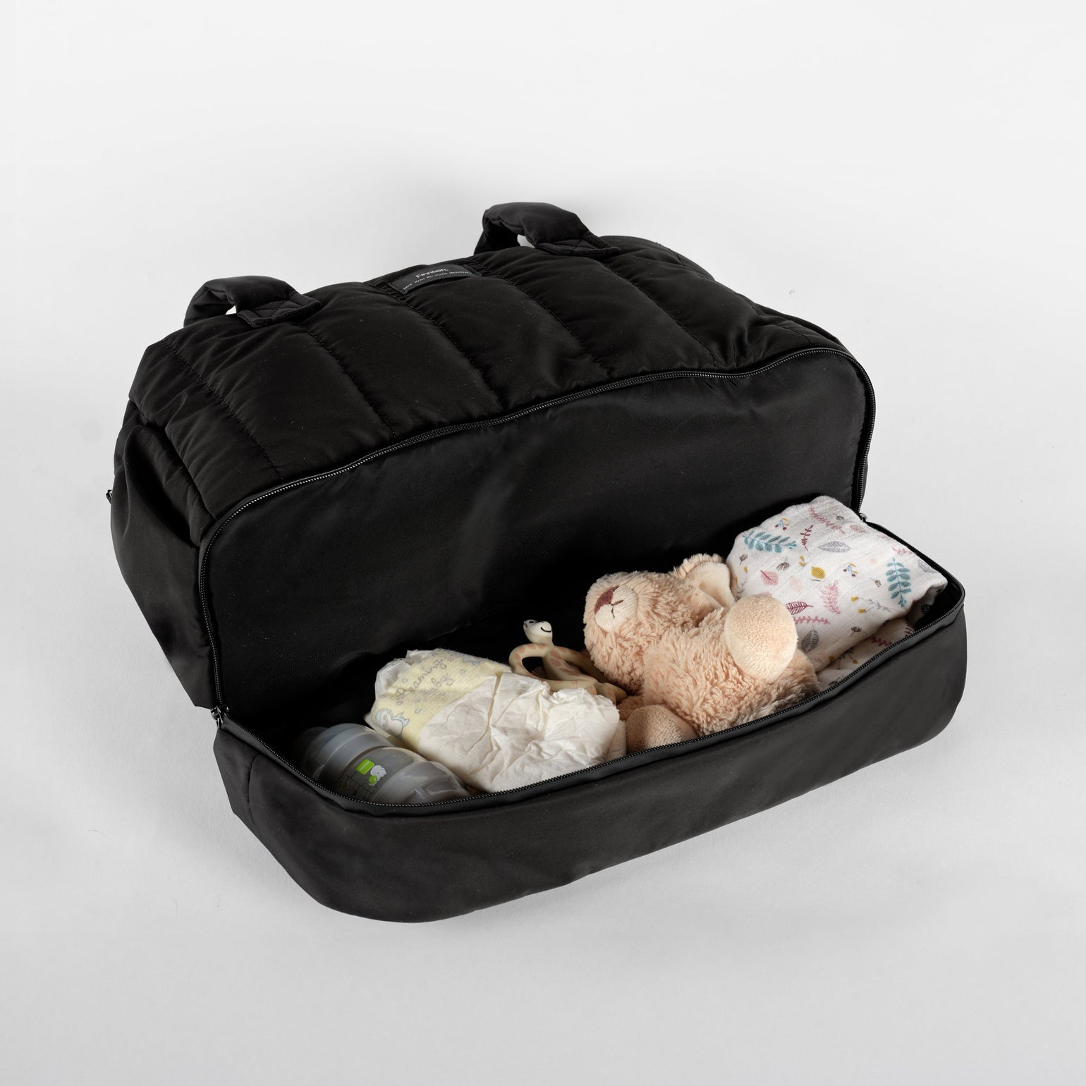Innes quilted black changing bag opened featuring the bottom pocket showing it spacious space