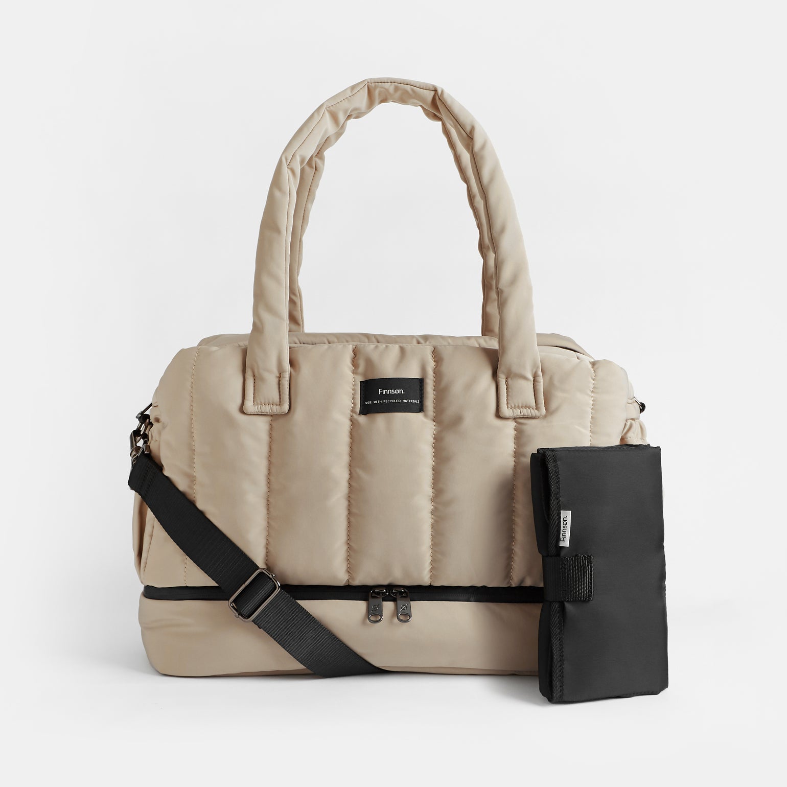 A taupe INNES quilted changing bag with a changing mat, featuring a zip base compartment, sturdy handles, a crossbody strap, and side D-rings.