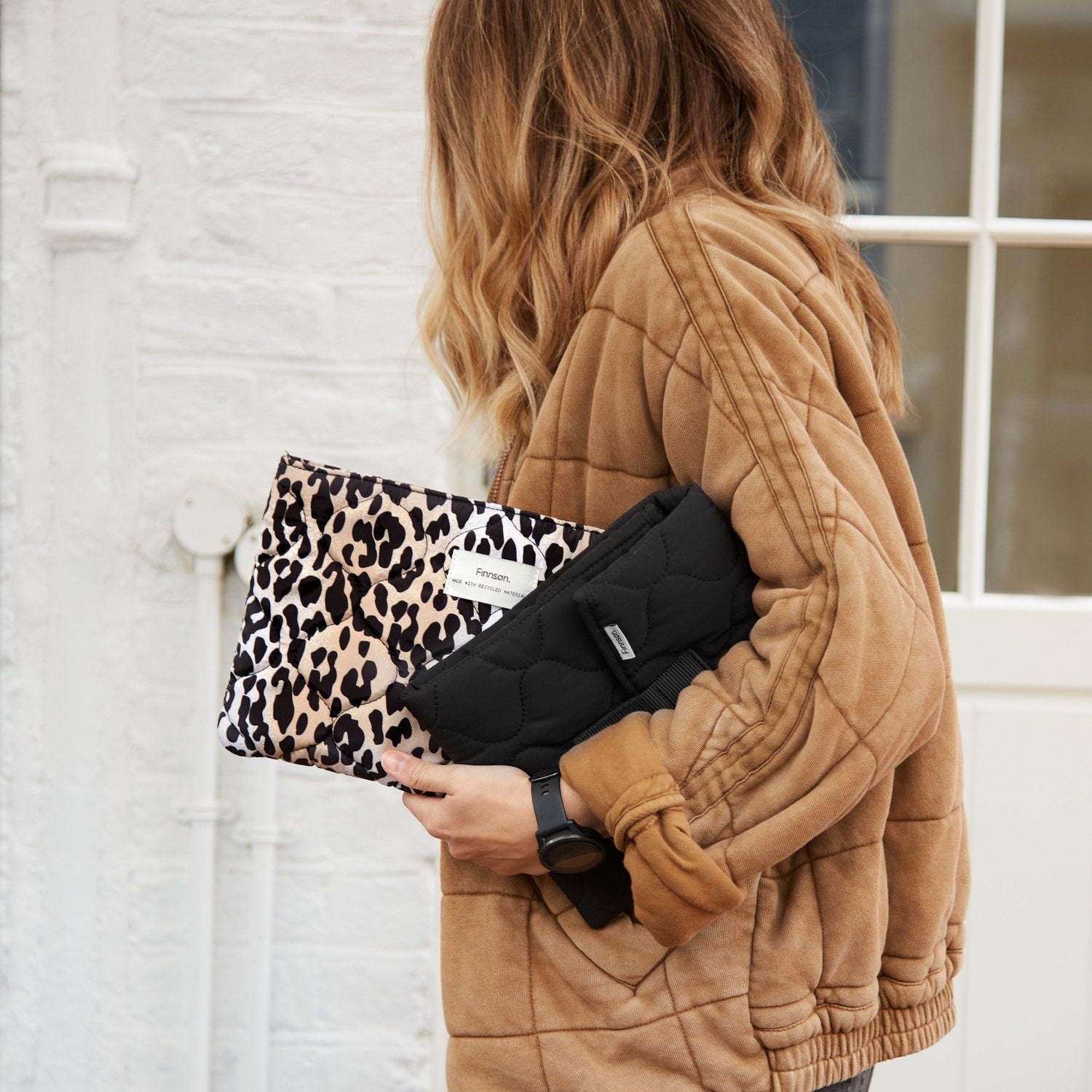 A woman holding the Kari black and leopard print changing mats