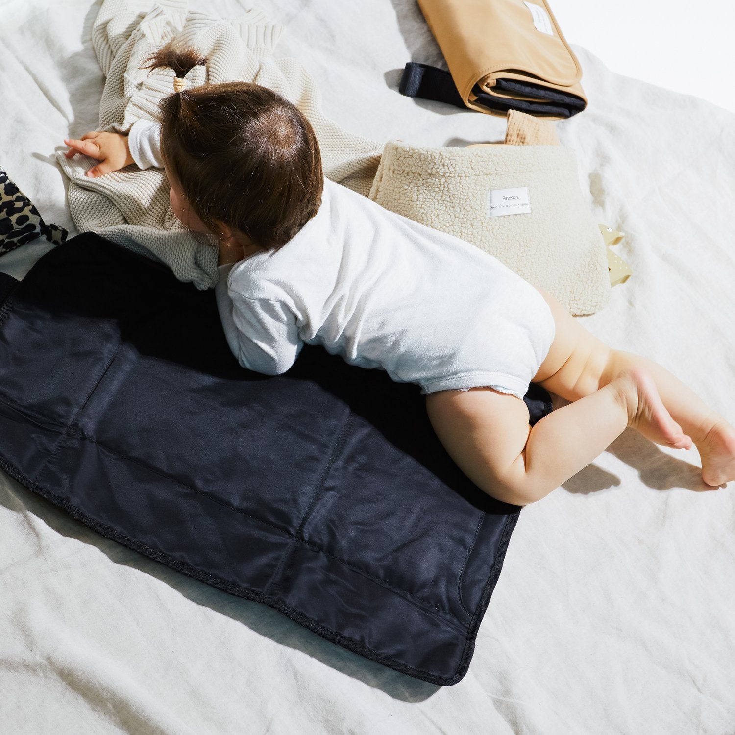 Kari Black changing mat with a baby lying comfortably on the padded black mat, demonstrating its soft, spacious, and practical design for diaper changes at home or on the go.