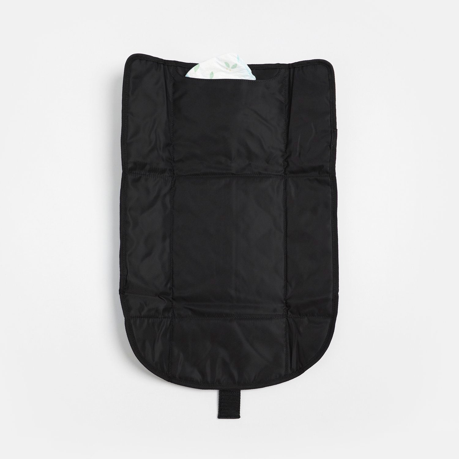 Kari Black changing mat laid flat with a built-in pocket holding a diaper, showcasing its padded surface, compact storage pocket, and practical design for convenient diaper changes.