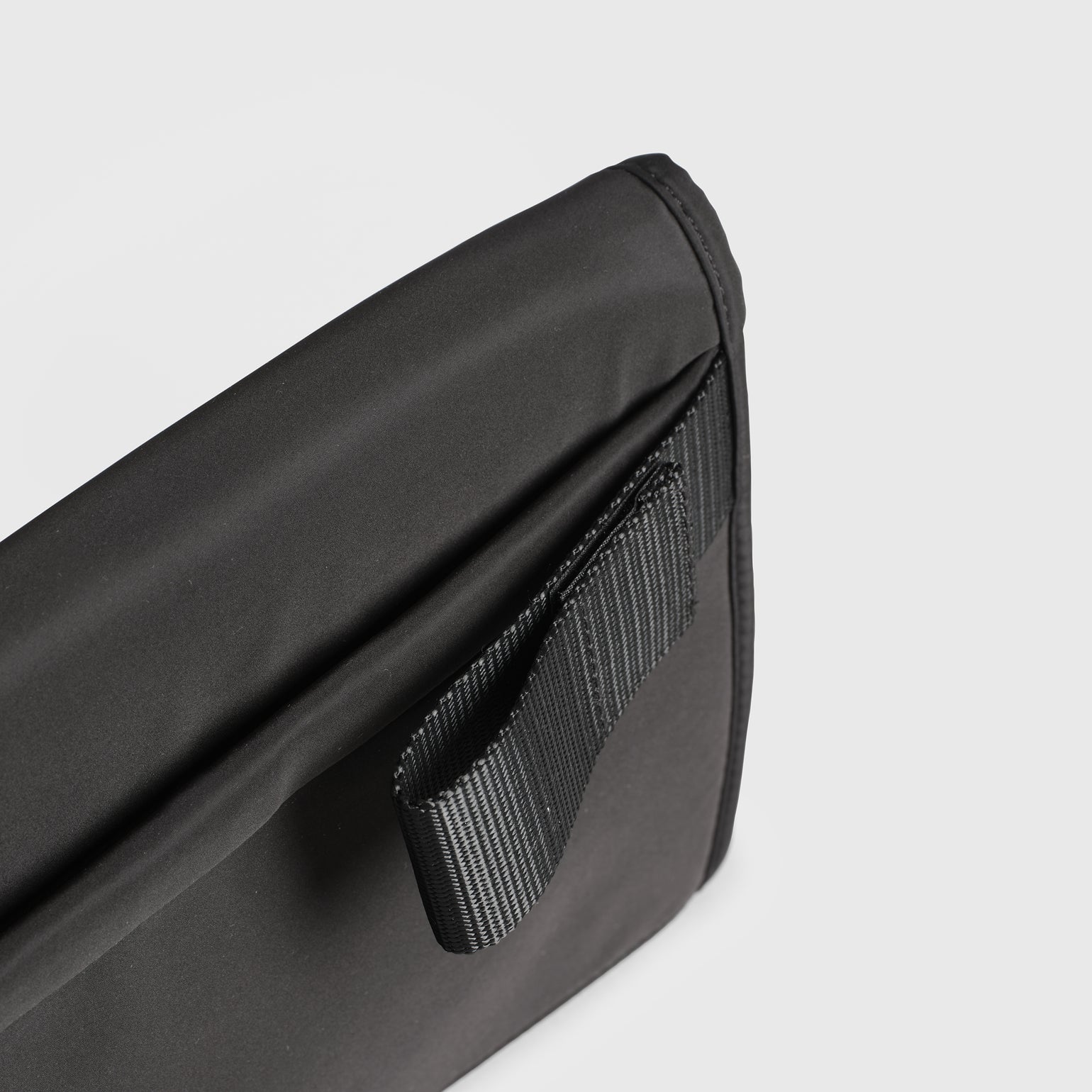 A Oslo black travel changing mat with a black webbing strap, shown on a light gray background.