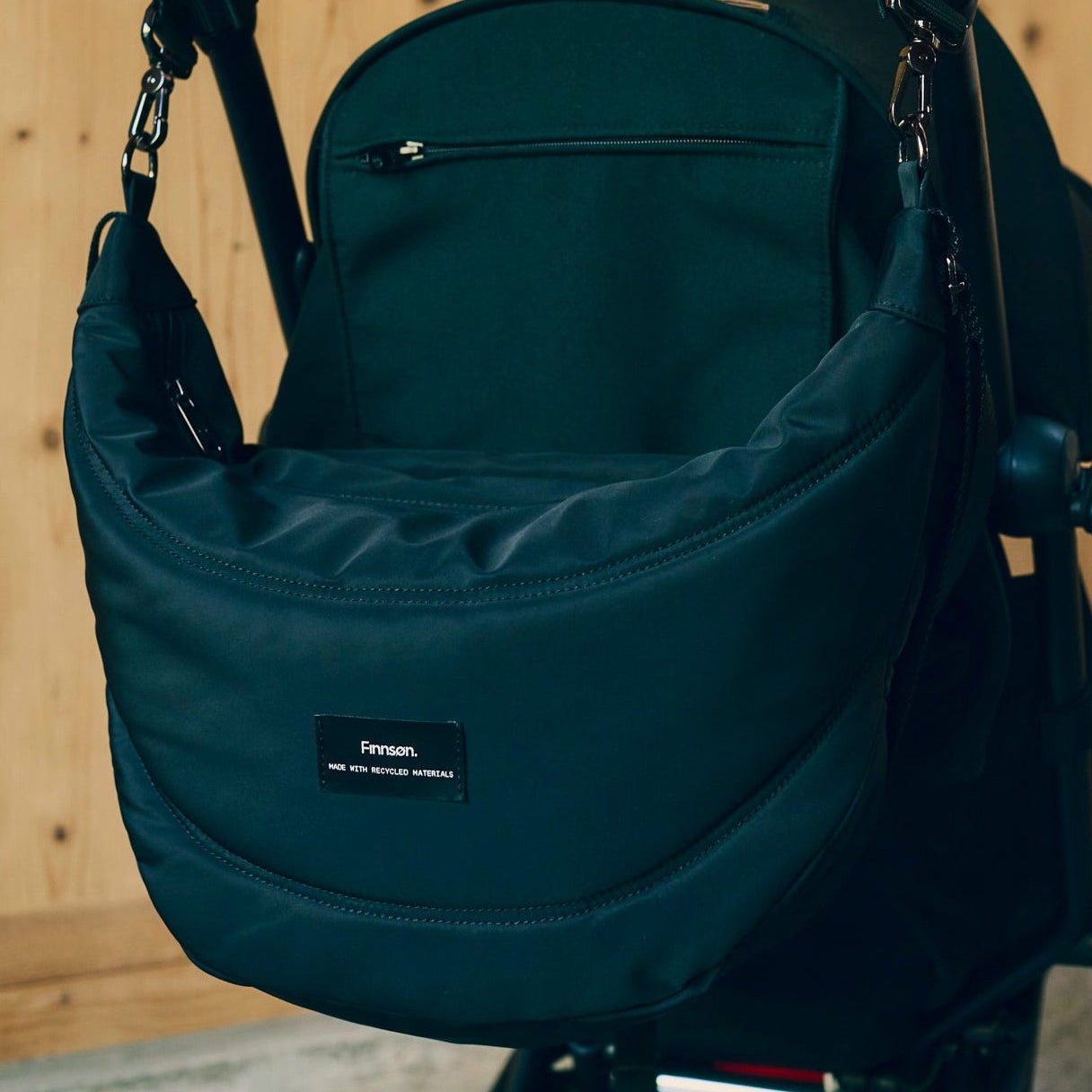 Osma stroller organiser black bag with a visible brand label on a wooden surface