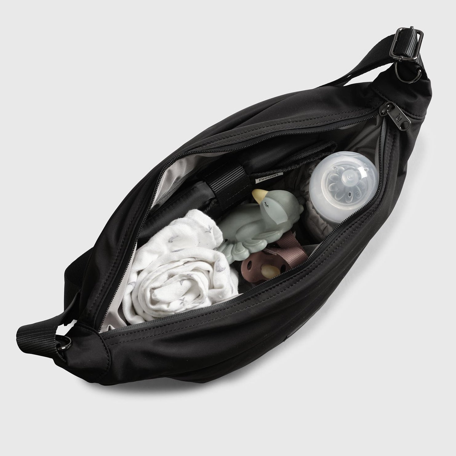 Osma stroller organiser black bag with baby items including a bottle and clothes on a light gray background