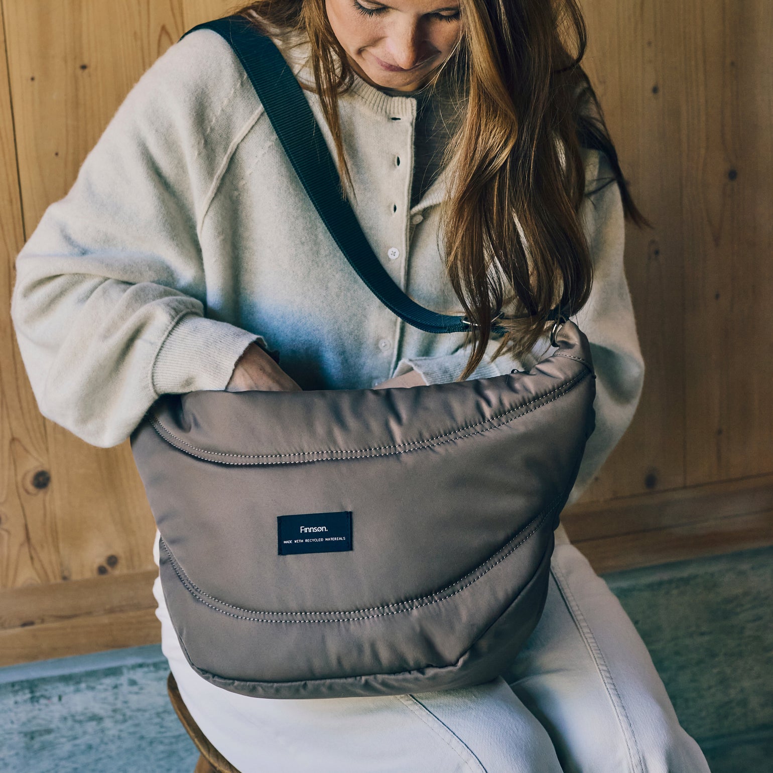 Woman holding osma mocha stroller organiser with a visible finnson brand label against a wooden background