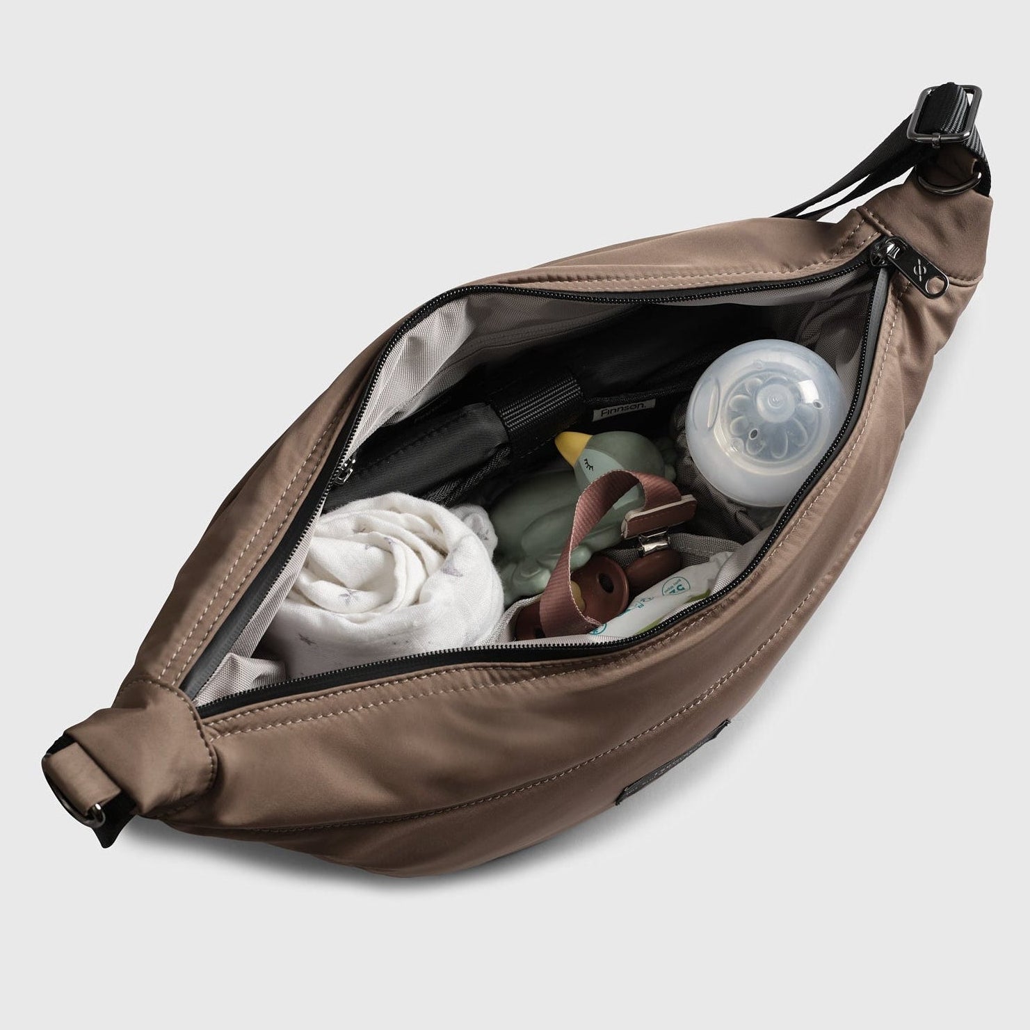 Osma mocha stroller organiser sling bag with items including a bottle and clothes on a light gray background