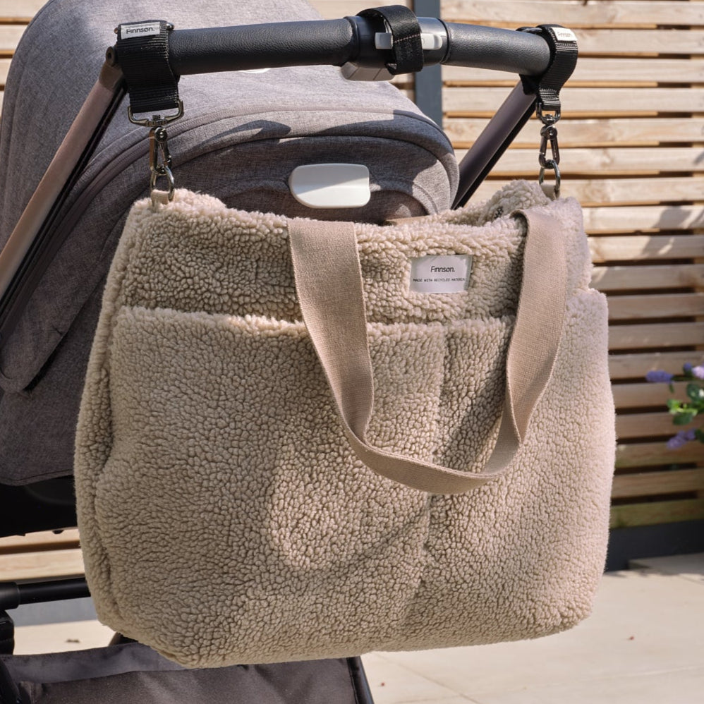 Sigrid mocha borg changing bag attached to a stroller with a wooden background