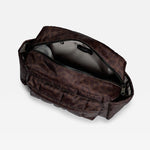 A dark brown leopard-print toiletry bag shown open, revealing a black interior, on a light gray background.