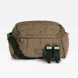 A mocha crossbody bag with a black adjustable shoulder strap and two black elastic side straps, shown against a plain white background.