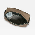 A mocha diaper bag shown open, revealing a dark gray interior and a clear plastic liner inside, set against a plain light gray background.