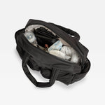 The Finnson Iris changing shown from an overhead angle with its main compartment open, revealing baby items inside such as a bottle, diaper, and small accessories, on a clean white background. 