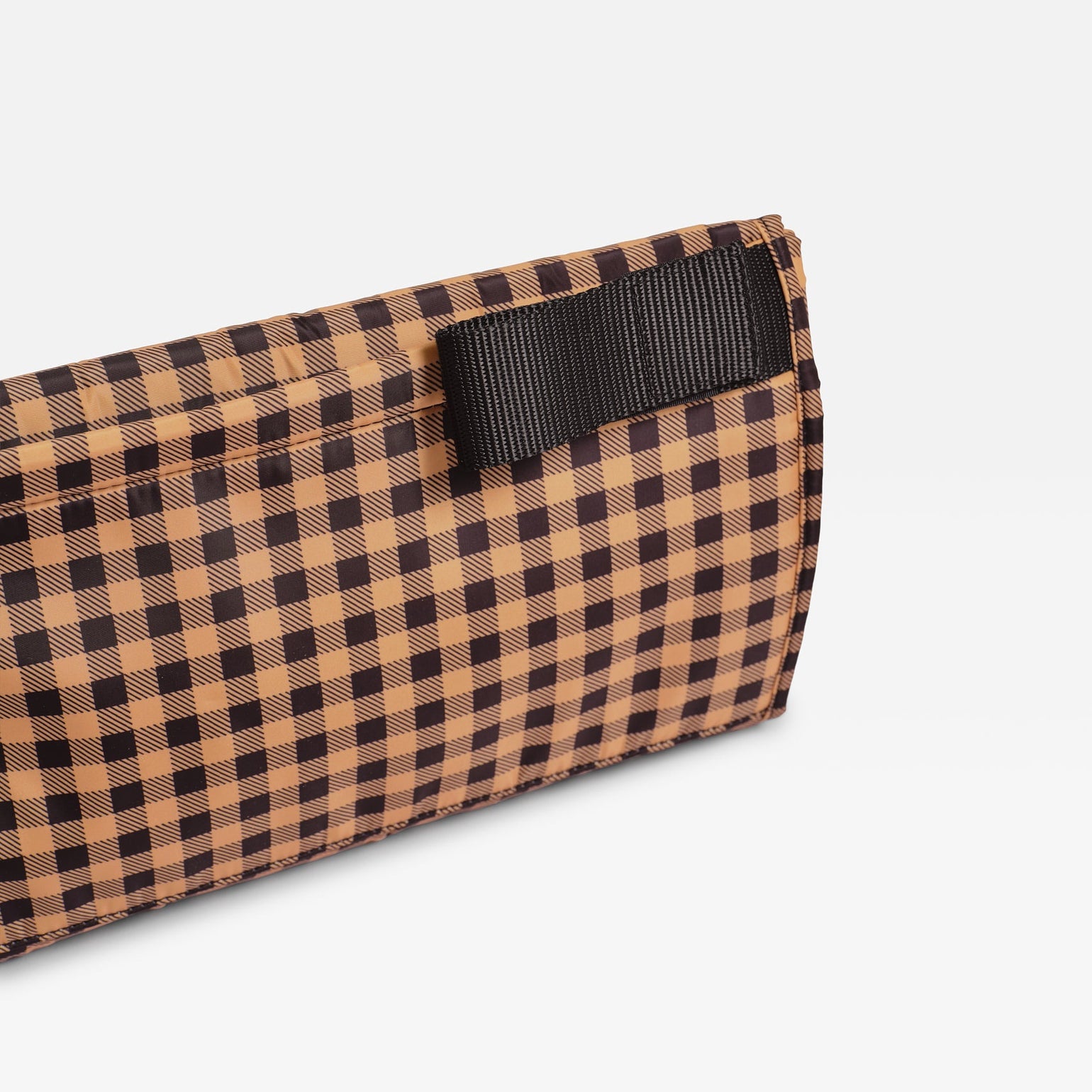 A close-up of Oslo gingham check patterned travel changing mat with a black webbing strap, shown on a light gray background.