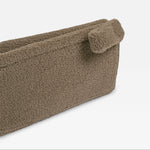 A close-up of a mocha bouclé fabric pouch or organizer with a small loop tab on the side, shown against a plain white background.